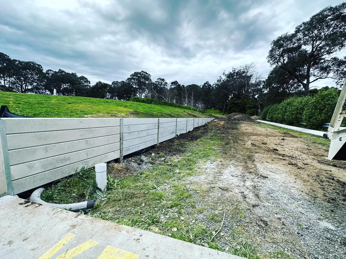 Long concrete sleeper retaining wall along a sloped access road