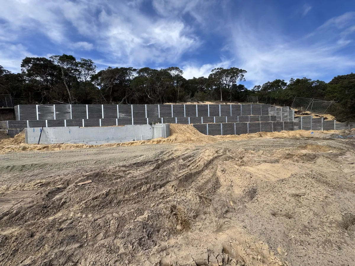 Long dark sleeper retaining wall on a sandy bushland site